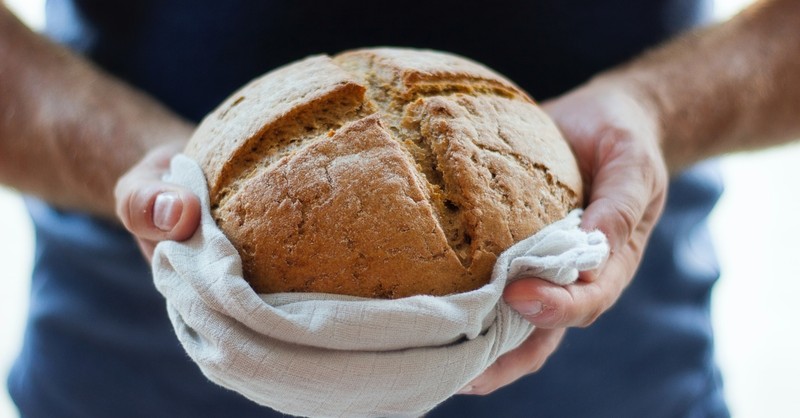 A person holding out a loaf of bread, love my neighbor