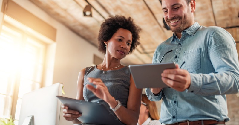 diverse man and woman at work on touchpad screens