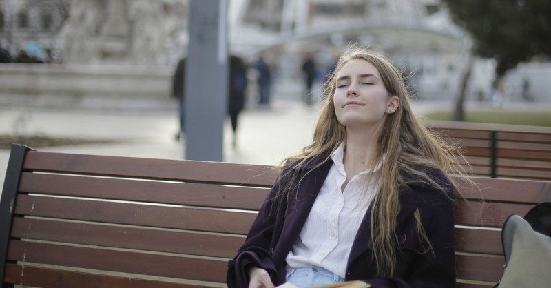 Woman relaxing on park bench enjoying sabbath; the fourth commandment.