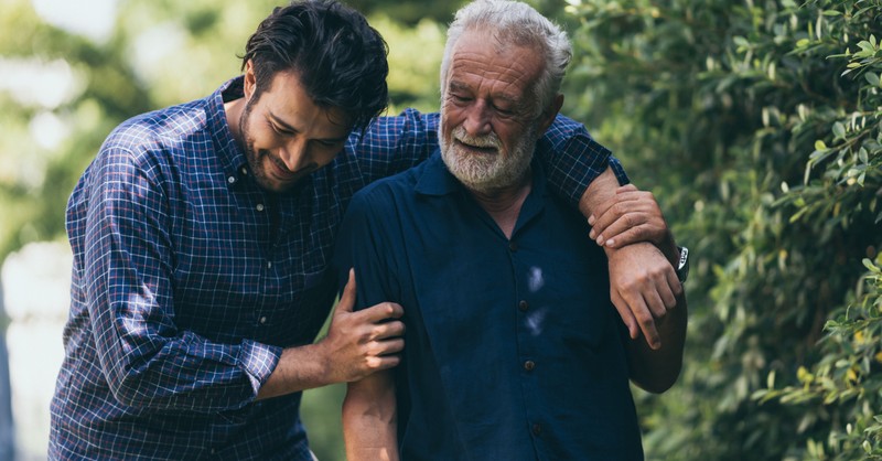 adult son with senior dad walking outdoors in park forgiveness healing