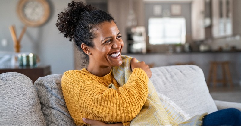 Woman smiling on her couch, love is patient love is kind