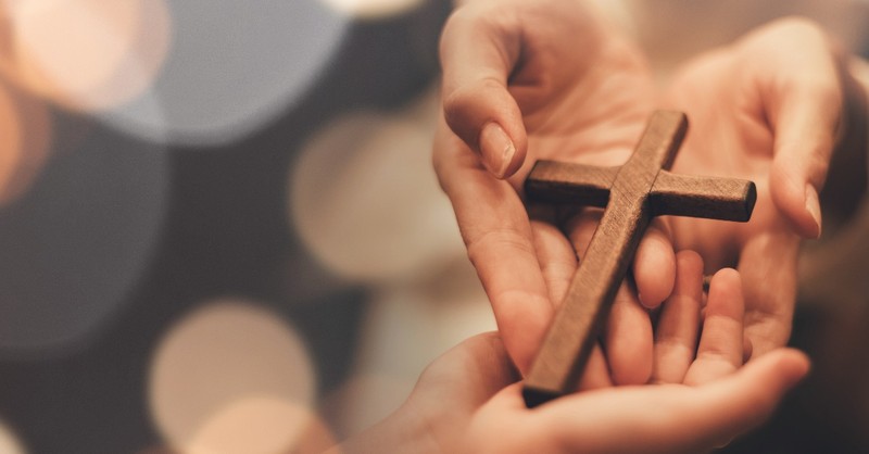 Hand holding a cross forming a heart shape, love is patient love is kind