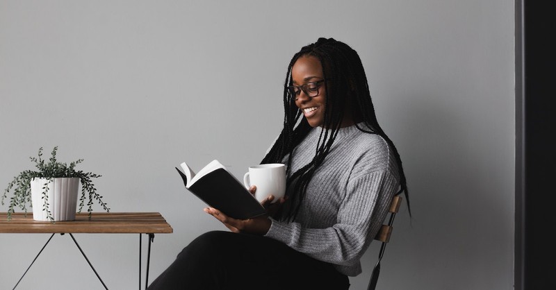 happy woman reading Bible with coffee at table