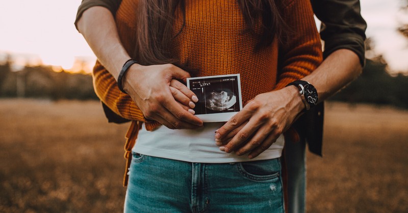 Couple embracing and holding up an ultrasound photo