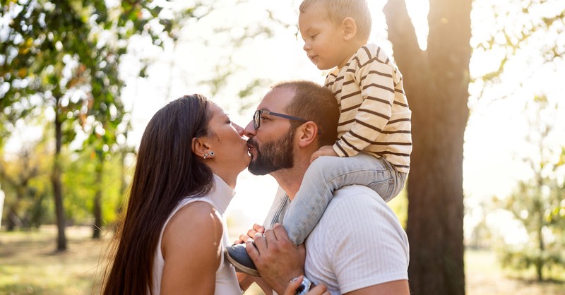 Happy couple parents kissing with son