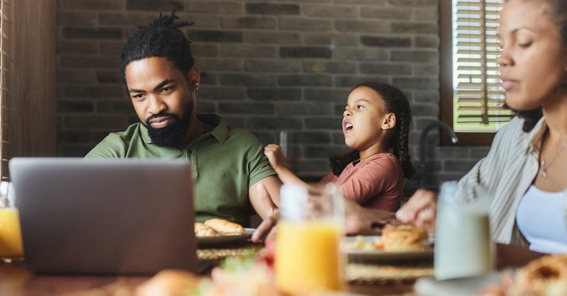 Dad working remotely at home on laptop ignoring kids