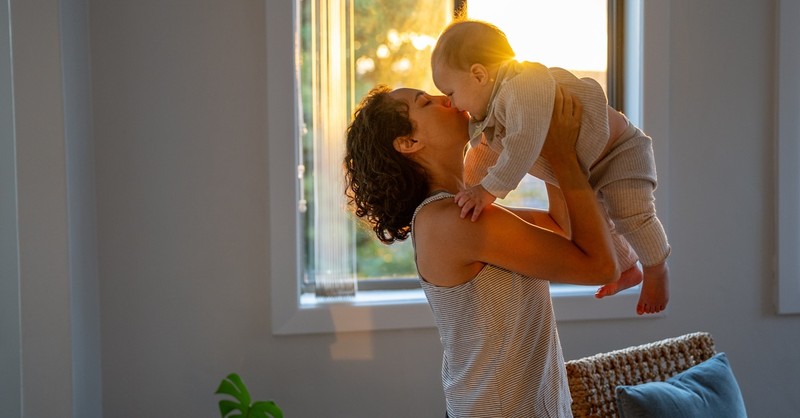 Mom kissing baby child in nursery