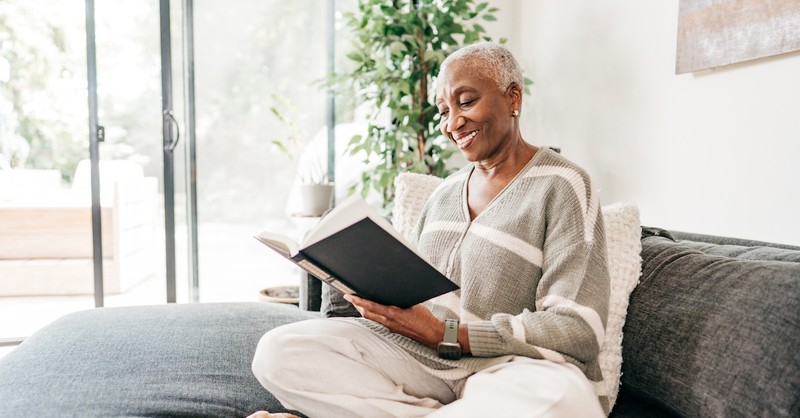 Senior woman on couch resting reading book